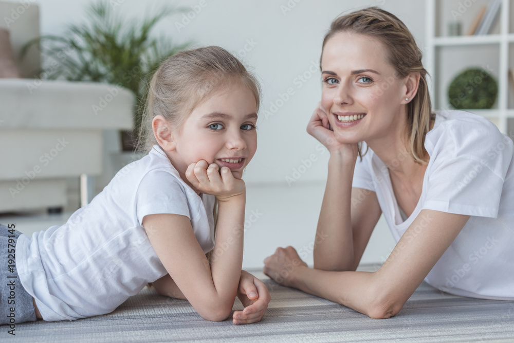 mother and daughter lying on floor together and looking at camera mother and daughter lying on floor together and looking at camera