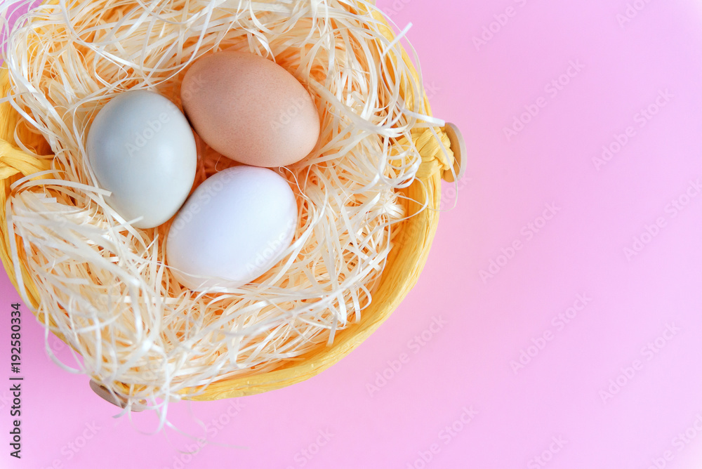 Easter eggs of different colors in a wicker basket on a pink background, Top view, Flat lay. Easter concept. Easter eggs of different colors in a wicker basket on a pink background, Top view, Flat lay. Easter concept.