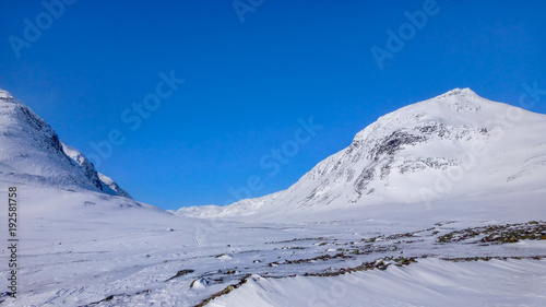 Two large snowy mountains in Sweden near the polar circle. Clear blue sky a sunny day.