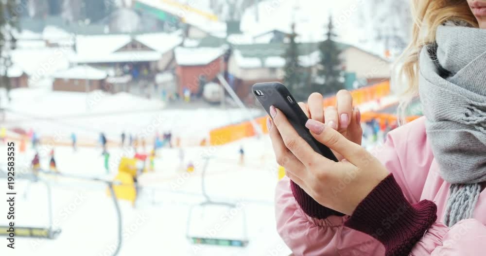 closeup girl hand holding using smart phone outdoor winter mountain resort skiing ski lift tapping touching screen application map gadget tech e-business email typing connect chat online web browser