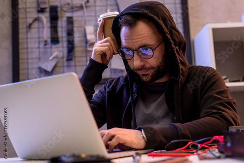 man in hoodie using laptop on table