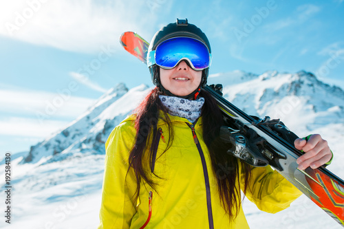 Picture of girl in helmet, mask with skis on her shoulder