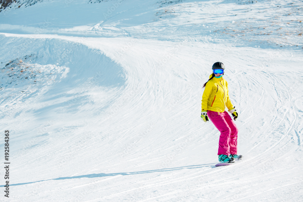 Photo of sports girl in helmet riding snowboard from mountain slope