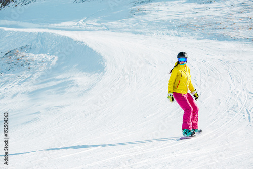 Photo of sports girl in helmet riding snowboard from mountain slope