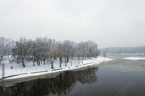 Winter landscape of the Dnipro River and park at the bank. Snow covers tree's brunches and ground. Kyiv, Ukraine