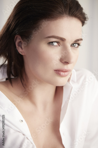 brunette woman with blue eyes and white shirt portrait