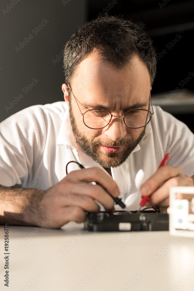 man using multimeter while testing hard disk drive man using multimeter while testing hard disk drive