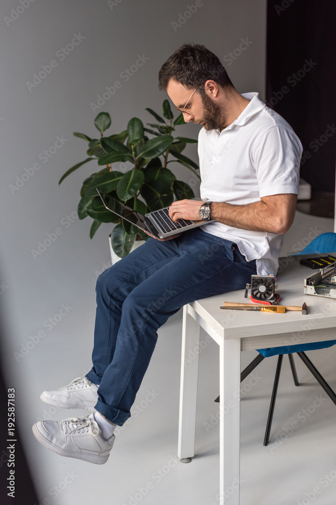 man sitting on table and using laptop