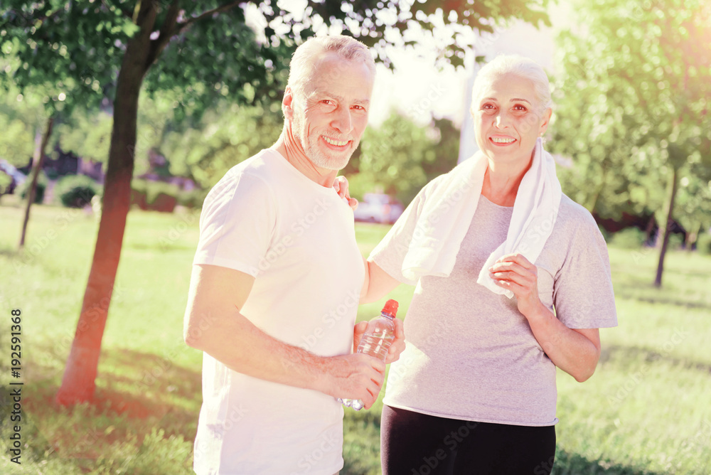 Time together. Waist up of optimistic couple standing close to each other while looking at you with a smile Time together. Waist up of optimistic couple standing close to each other while looking at you with a smile