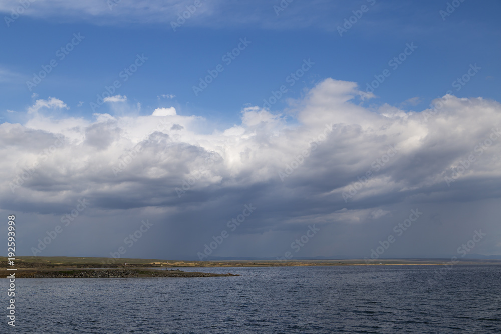 A large reservoir ( lake ) in Kazakhstan under a cloudy and rainy sky