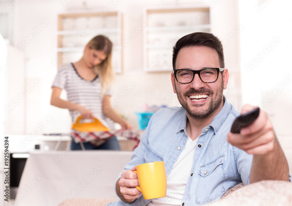 Man watching tv and woman doing housework Man watching tv and woman doing housework