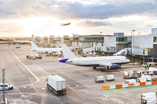 Busy airport view with airplanes and service vehicles at sunset photo