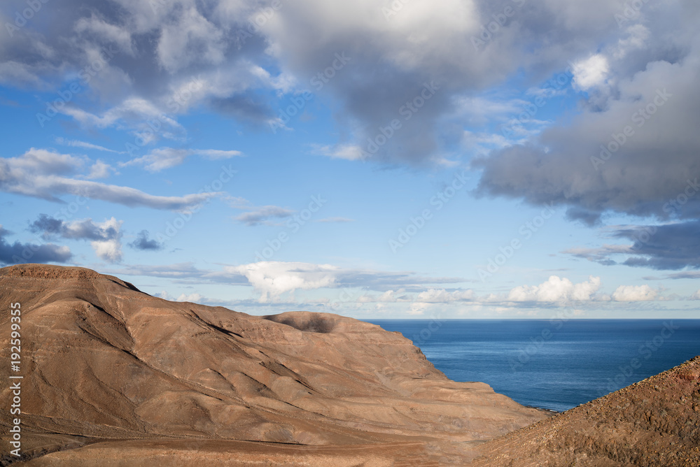 arid coastal scenery against beautiful sky and blue ocean