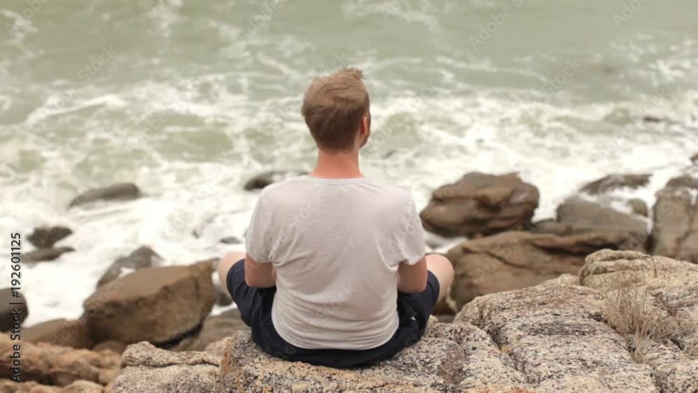 man is resting on the rocks on the seashore man is resting on the rocks on the seashore