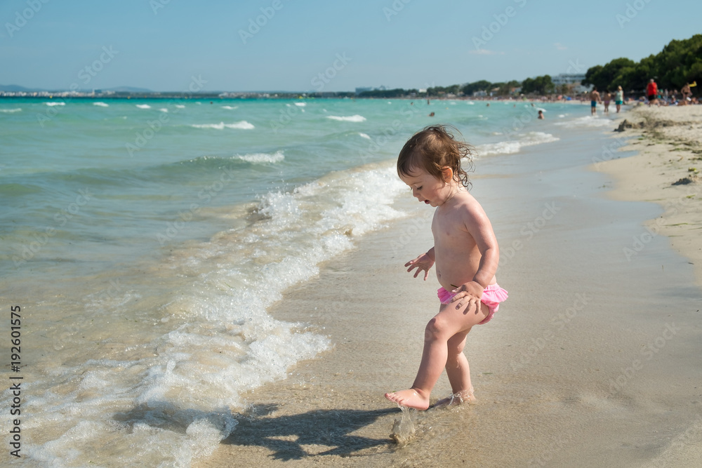 Cute small girl in a pink swimsuite walking on the beach Cute small girl in a pink swimsuite walking on the beach
