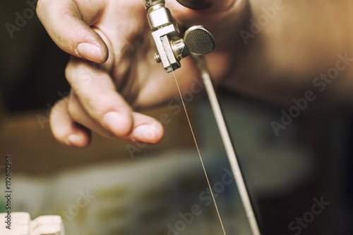 Jewelry maker cutting sterling silver with a band saw