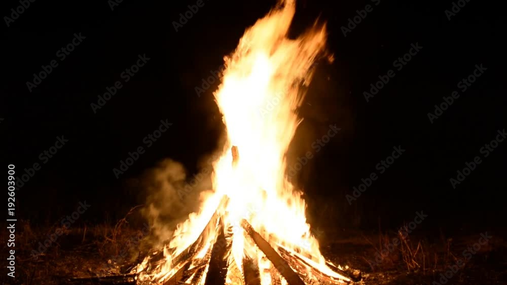 A big fire from the logs and trees in the clearing. Night, summer. 