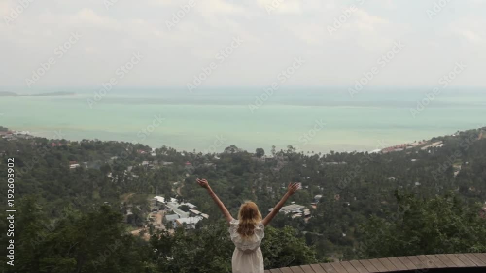 girl pulls her hands up standing near the cliff overlooking the tropical island girl pulls her hands up standing near the cliff overlooking the tropical island