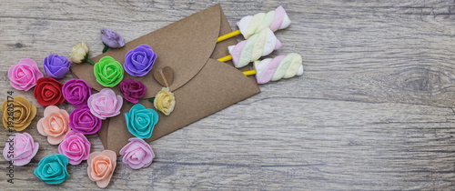 Present, surprise, love concepts. Marshmallow candies in the envelope decorated with multi-colored flowers.