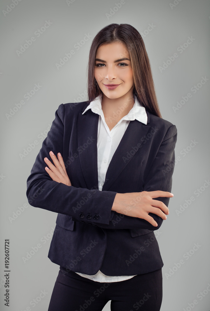 Casual business woman with arms crossed and smiling on gray background Casual business woman with arms crossed and smiling on gray background
