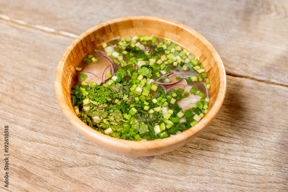 Onion asian soup served in the wooden plate on the table Onion asian soup served in the wooden plate on the table