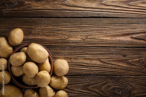 Fresh potato food. Pile of raw potatoes lying  on old wooden table. Concept of food background. Free place for text, top view.