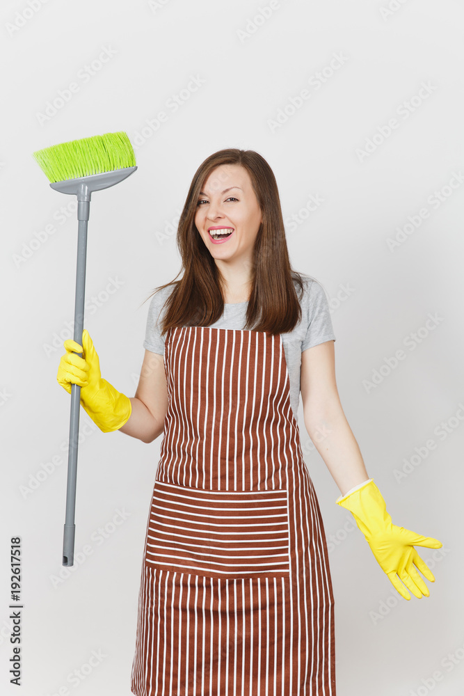 Young smiling housewife in striped apron, yellow gloves isolated on white background. Housekeeper woman cleaning maid holding and sweeping with broom. Copy space for advertisement. Advertising area. Young smiling housewife in striped apron, yellow gloves isolated on white background. Housekeeper woman cleaning maid holding and sweeping with broom. Copy space for advertisement. Advertising area.