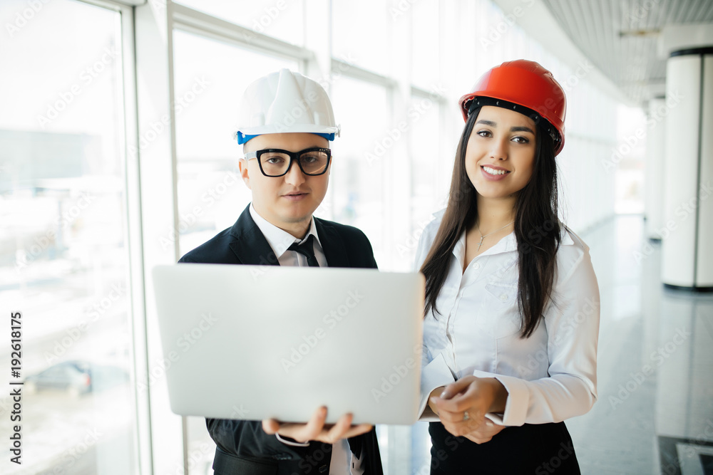 Engineering and architecture concept. Engineers working on a building site holding laptop, architect man working with engineer woman inspection in workplace for architectural plan Engineering and architecture concept. Engineers working on a building site holding laptop, architect man working with engineer woman inspection in workplace for architectural plan