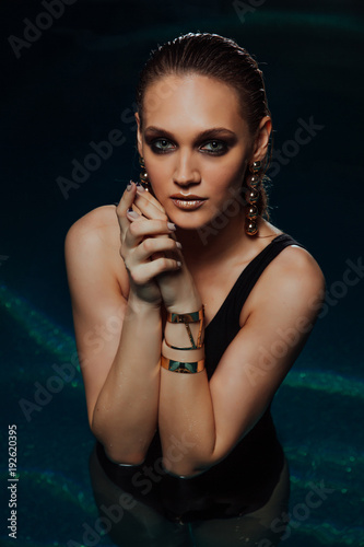 Fashion Sexy portrait of a girl in the pool. Woman's Black swimsuit, turquoise water in the spa.