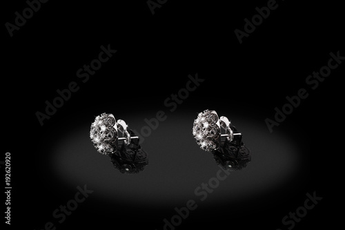 Platinum precious earrings with big diamonds on black background.