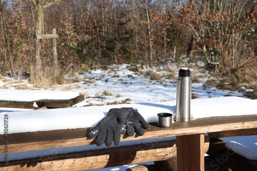 picnic scene with thermos cup and gloves