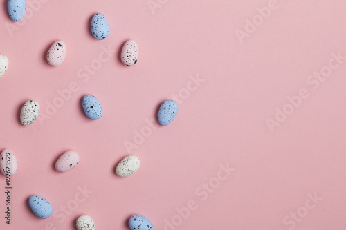 A collection of easter eggs on a pastel pink background