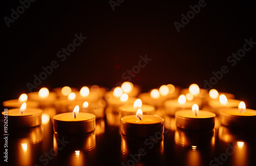Burning candles. Shallow depth of field. Many christmas candles burning at night. Abstract candles background. Many candle flames glowing on dark background. Close-up. Free space.