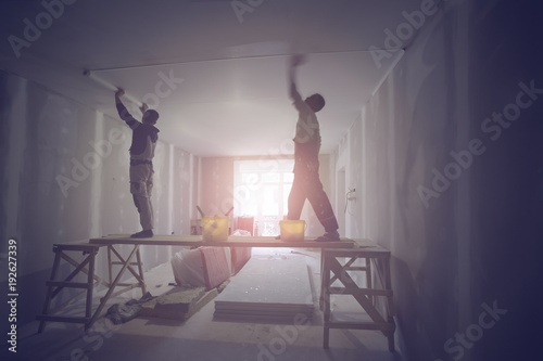 Workers are installing ceiling from wooden platform in apartment is under construction, remodeling, renovation, and reconstruction. Tone effect