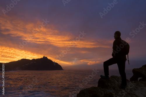 Traveler man looking at the landscape at sunset by the sea.