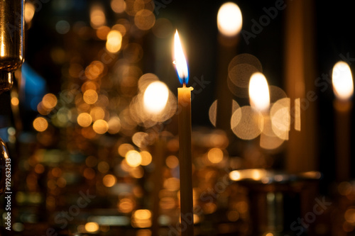 burning candles in a Church on a dark background with blurred bokeh of the candles