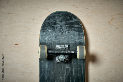 top view of black used skateboard on wooden background