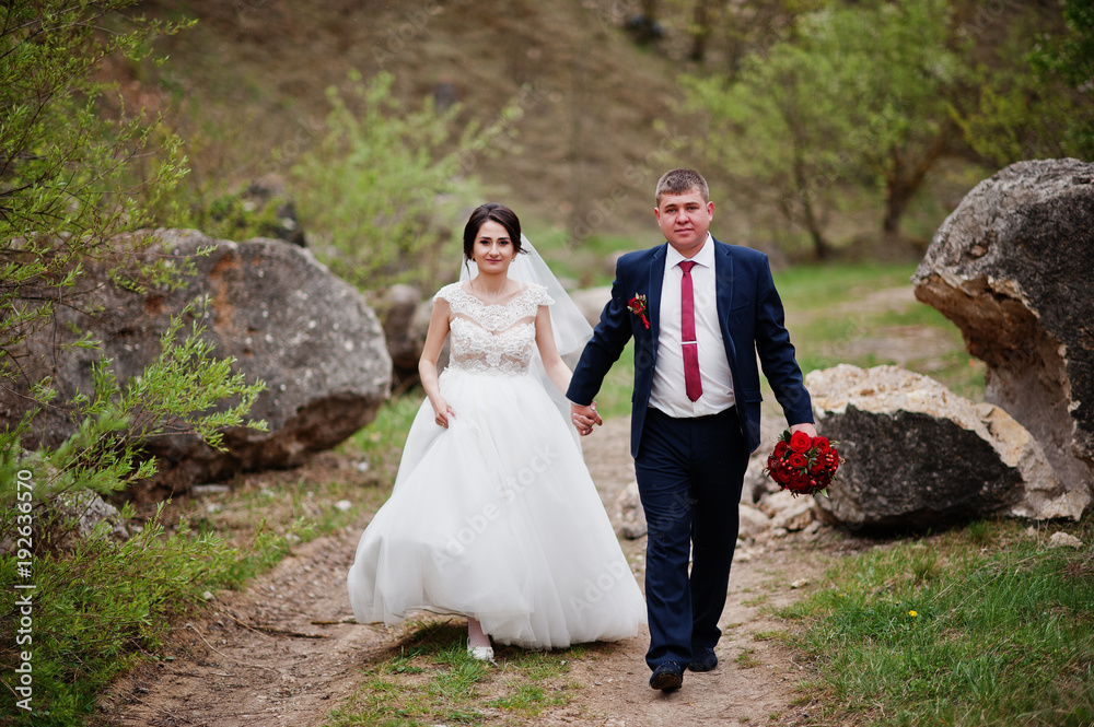 Romantic newly married couple posing and walking in rocky countryside on their wedding day.