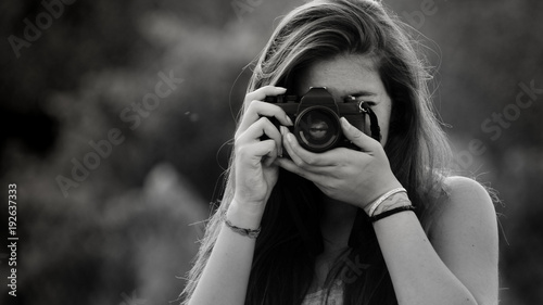 Ragazza che fotografa con macchina fotografica analogica vintage
