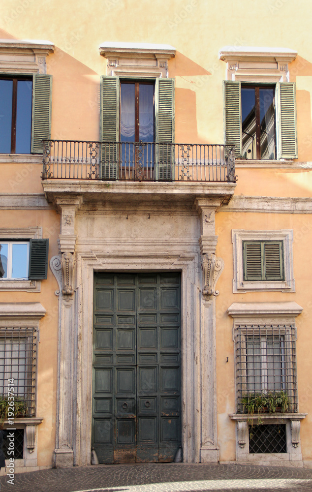 Building in Rome, details of old facade, wall with windows and wooden shutters.