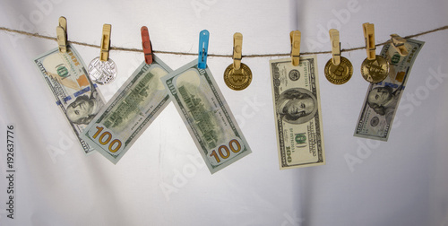 Money laundering concept. Yellow clothes peg hold Bitcoin and one hundred dollar banknotes photo