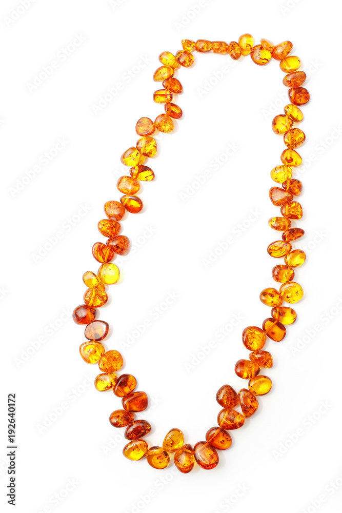 Amber beads on white background. Beads from polished pieces of amber of ancient petrified resin. Women's fashion jewelry beads. Vintage decoration. Jewelry made of natural stone. Amber beads on white background. Beads from polished pieces of amber of ancient petrified resin. Women's fashion jewelry beads. Vintage decoration. Jewelry made of natural stone.