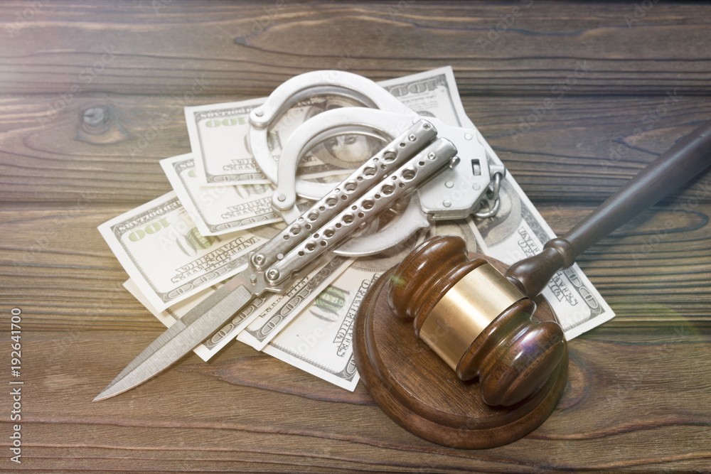 banknotes of dollars. knife, handcuffs, against the background of a wooden table. crime robbery. arrest