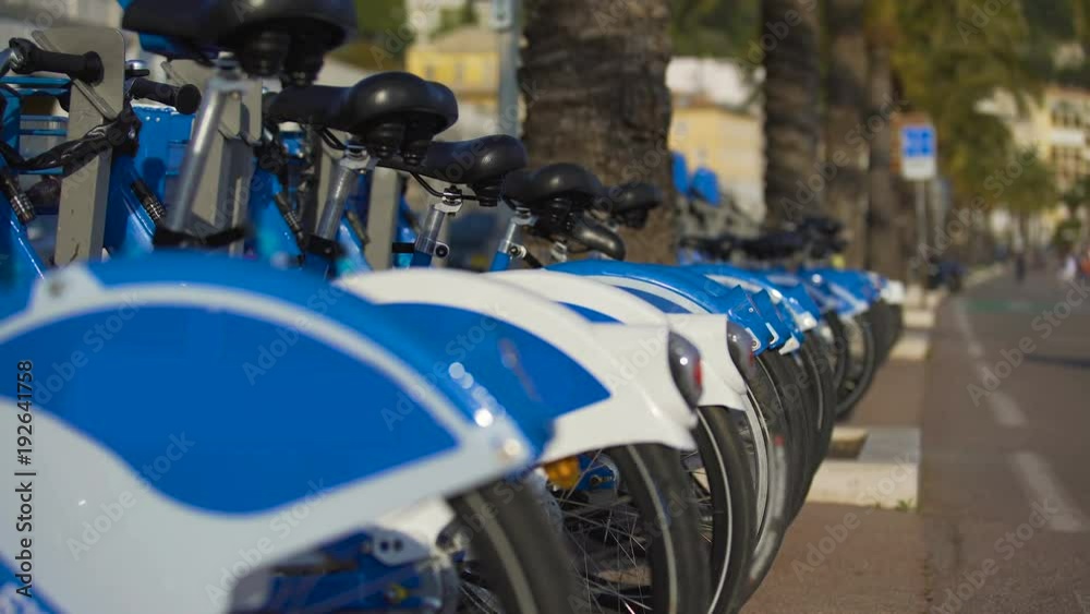 Blue eco-bicycles standing in row on street, bikes for hire, urban transport Blue eco-bicycles standing in row on street, bikes for hire, urban transport