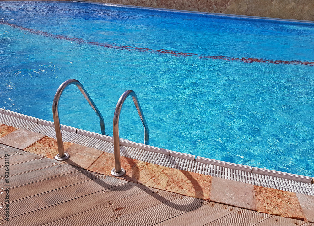 Grab bars ladder in the blue luxury swimming pool. Grab bars ladder in the blue luxury swimming pool.