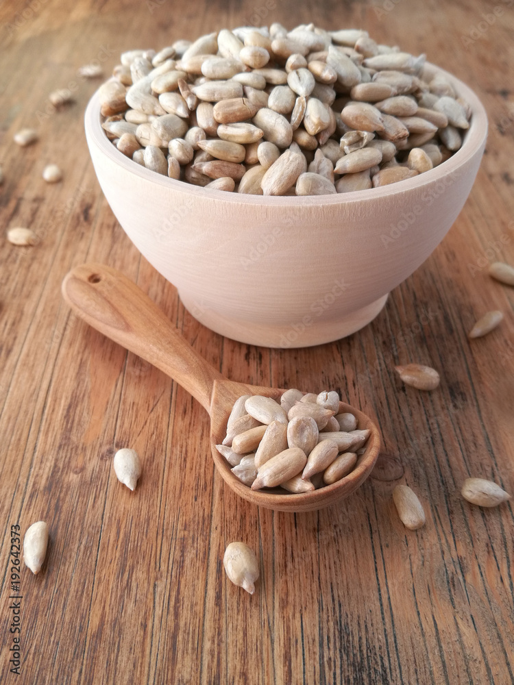 Sunflower seeds in a wooden bowl and a wooden spoon Sunflower seeds in a wooden bowl and a wooden spoon