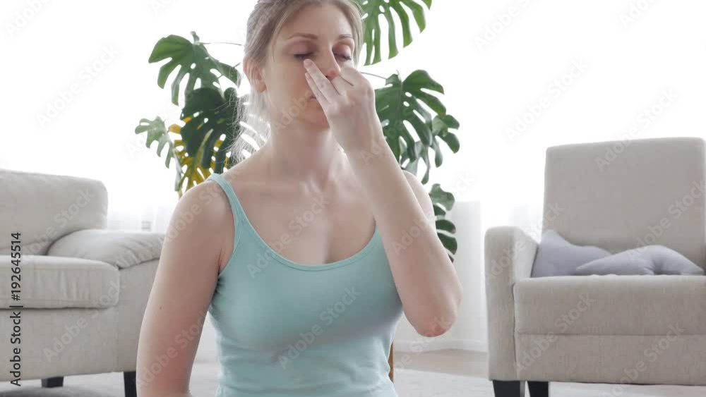 Concentrated female doing nostril breathing technique in lotus pose Concentrated female doing nostril breathing technique in lotus pose