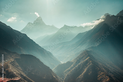 The breathtaking panoramic view the mighty misty snow-capped Himalayas and the canyons with the coniferous forests. Nepal. Ideal background for the various kinds of collages and illustrations. photo