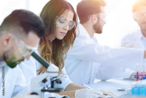scientist looking in a microscope sitting in the lab.