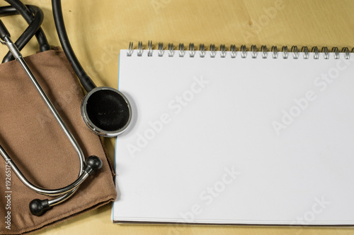 Medical accessories on a wooden table. Stethoscope, and a medical sphygmomanometer in the doctor's office.